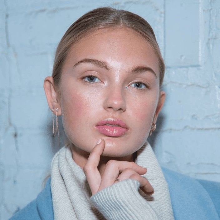 person with low bun posing with finger on chin