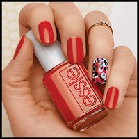 hand with nails painted red holding a bottle of red nail polish