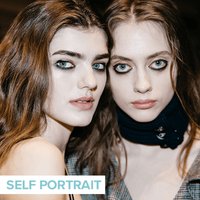 two people looking into camera posing and wearing dark eye makeup