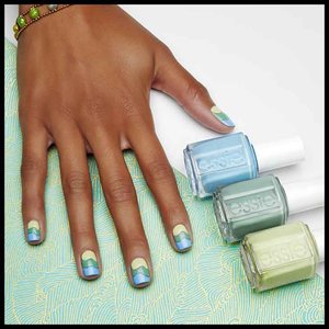 hand with nails painted blue and green pose next to nail polish bottles