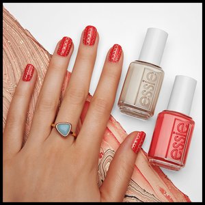 hand with nails painted red pose next to bottles of nail polish