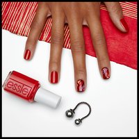 hand with nails painted red pose next to red bottle of nail polish