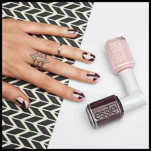 hand with nails painted with nail art pose next to bottles of nail polish