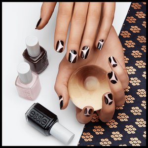 hands with nails painted with nail art posing next to bottles of nail polish