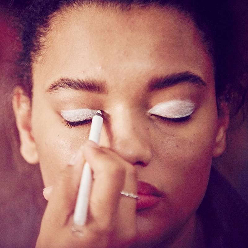 hand applying white eyeliner to someone's eyelid