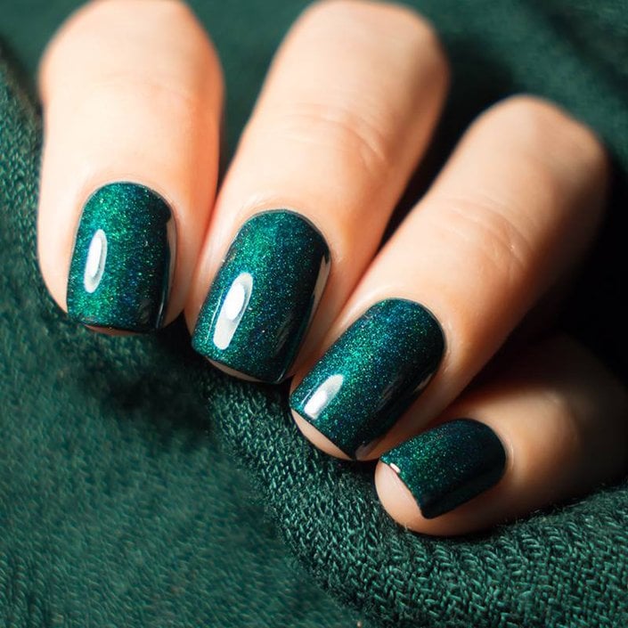 hand with nails painted with green glitter nail polish
