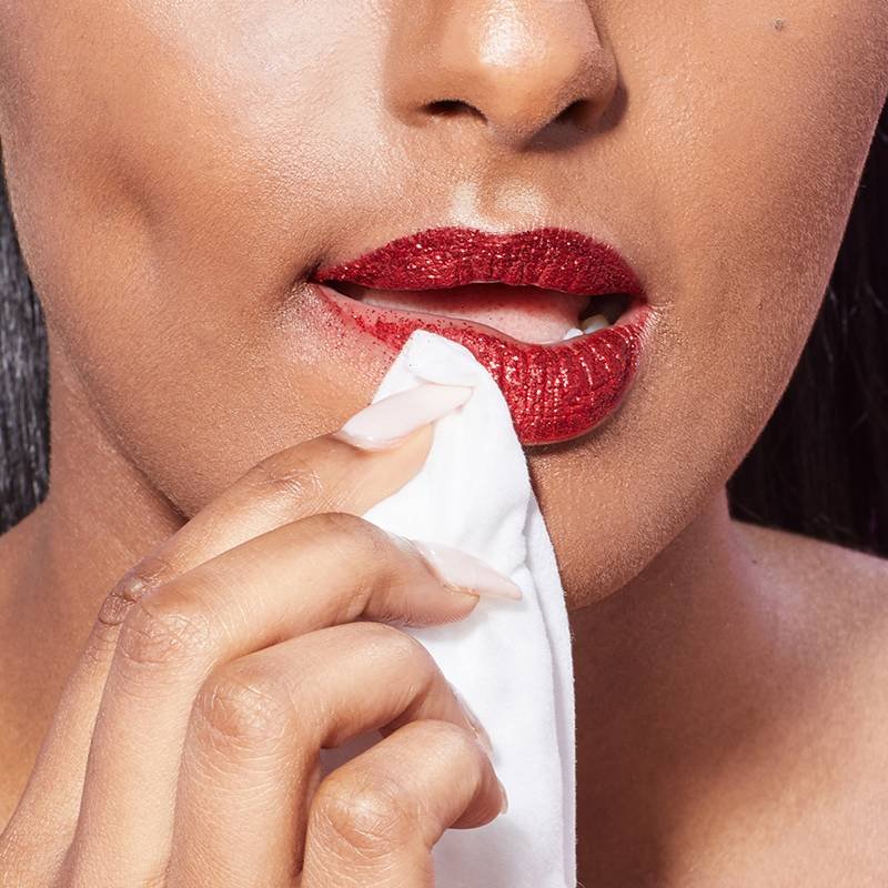 person wiping bottom lip with makeup remover wipe