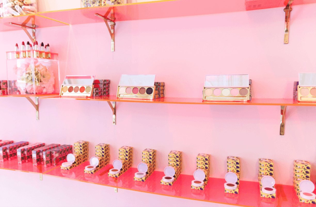 beauty products on pink shelves against a pink wall