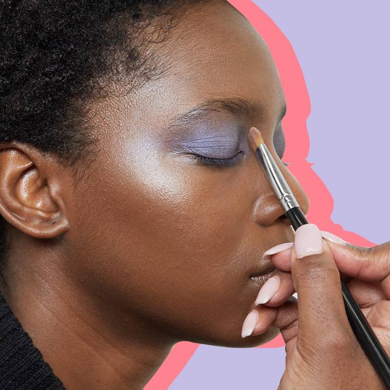 hand applying eyeshadow to someone's eyelid with makeup brush