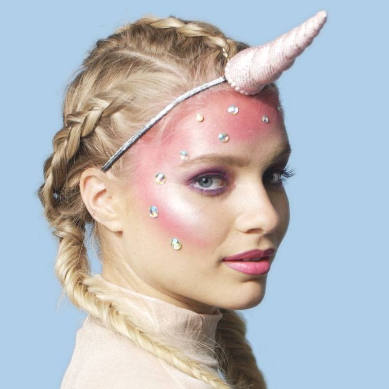 person wearing holographic face makeup and unicorn horn on head