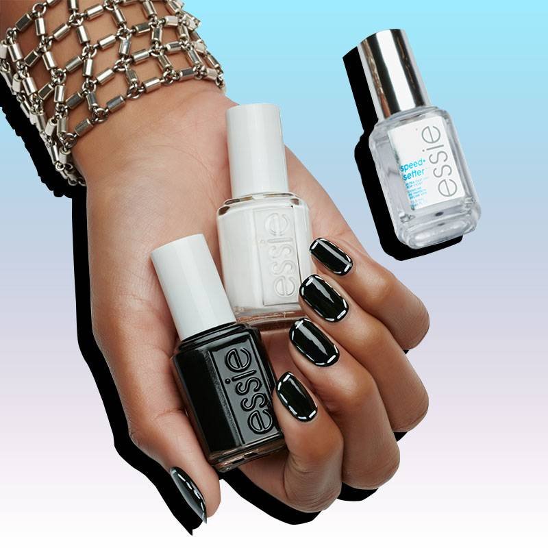 hand with nails painted black holding two essie nail polish bottles