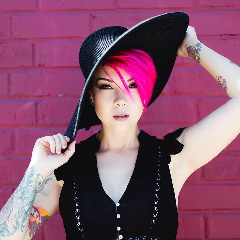 person with hot pink pixie cut wearing black hat and black shirt