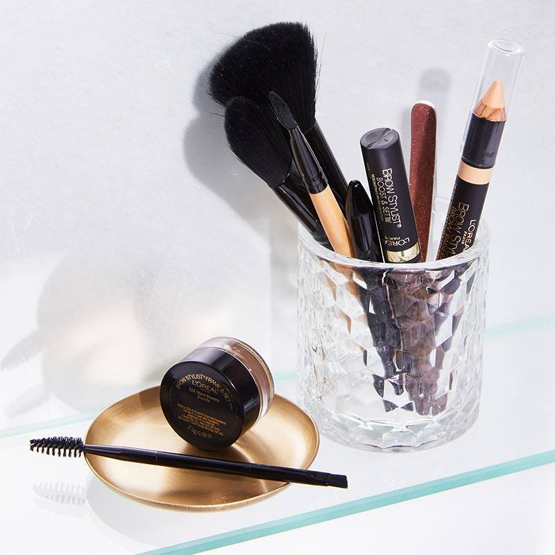 l'oreal paris brow products and makeup brushes in a glass cup