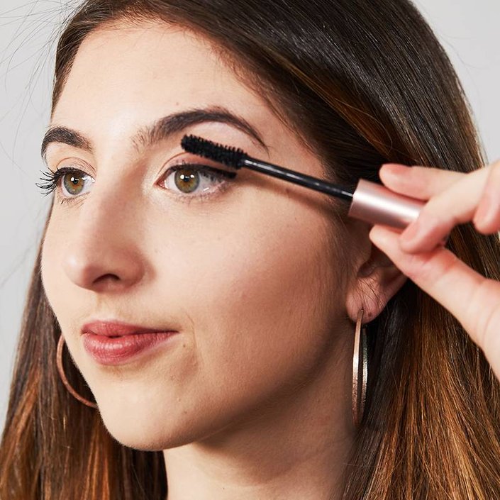 person holding mascara wand to eyelashes