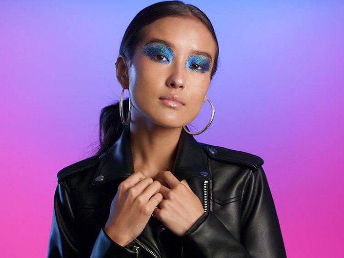 person wearing blue and green glitter eye makeup