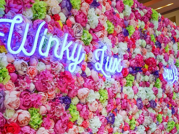 winky lux neon sign on flower wall