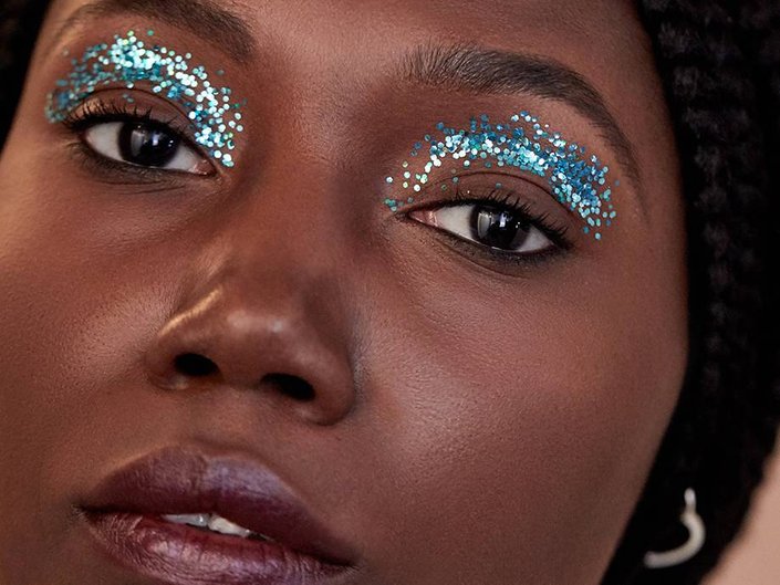 person wearing blue glitter eye makeup and burgundy lipstick