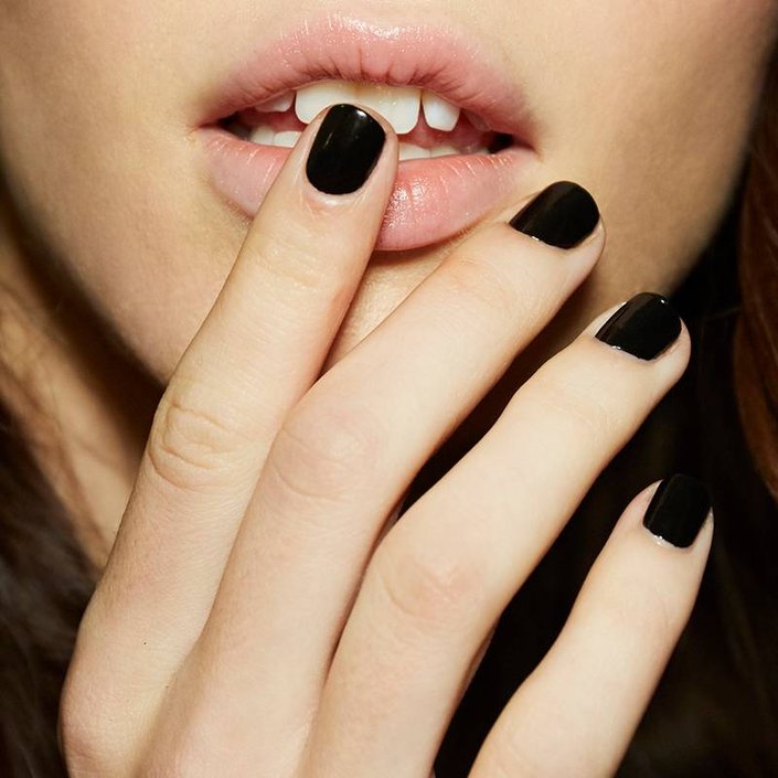 hand with nails painted black and finger touching person's bottom lip