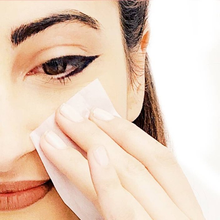 person holding blotting paper to cheek