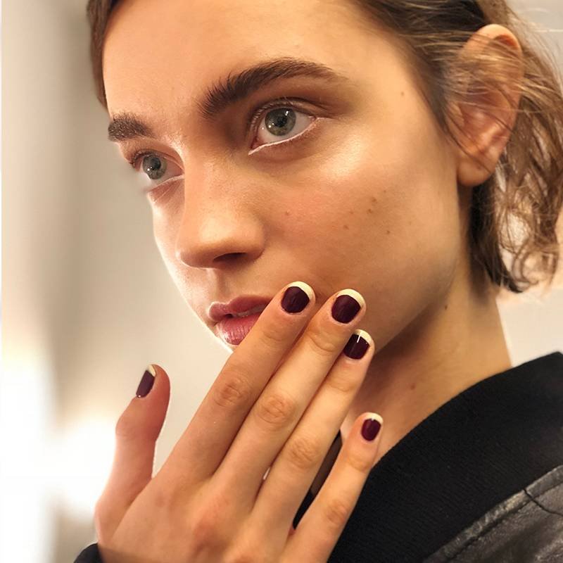 model backstage at fashion week with nails painted burgundy