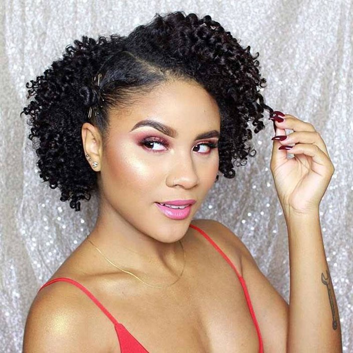 person with naturally curly hair wearing pink eyeshadow and lipstick