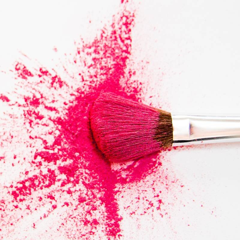 makeup brush covered in pink makeup powder