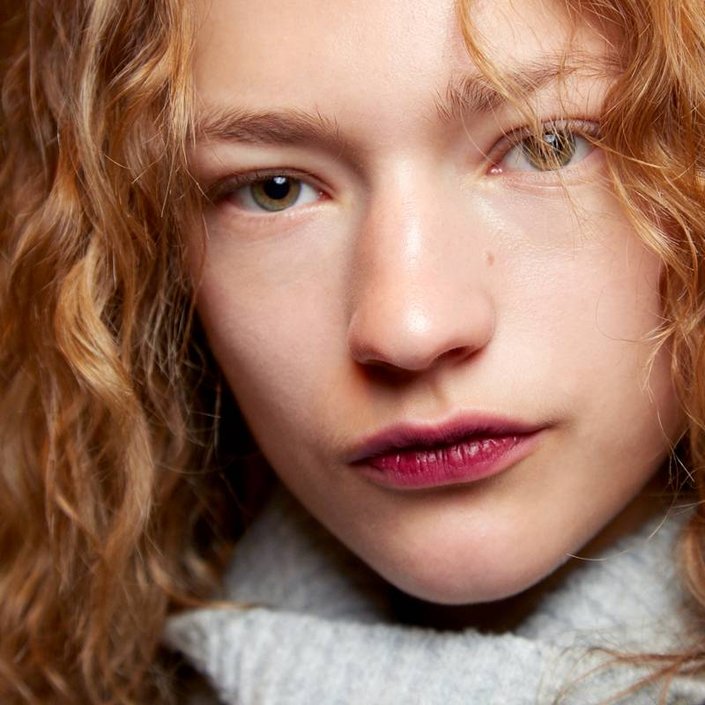 person with red hair wearing deep berry lip stain
