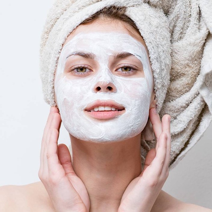 person wearing cream face mask and towel around head