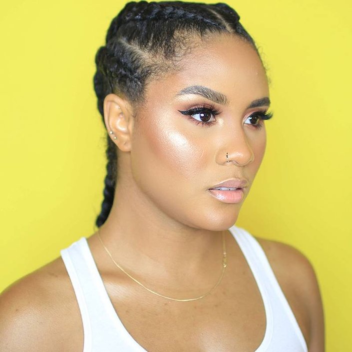 person with cornrows wearing highlighter on cheek and winged eyeliner