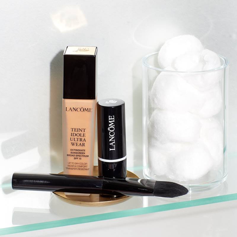 Lancôme Teint Idole Ultra Wear Foundation, Lancôme Blur + Go Priming Stick, a makeup brush, and cotton balls