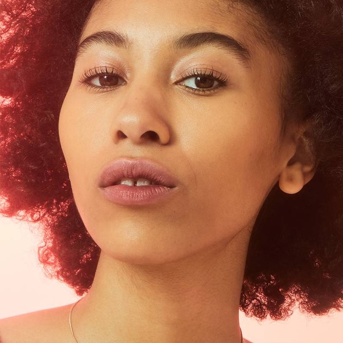 person with naturally curly hair wearing barely there makeup