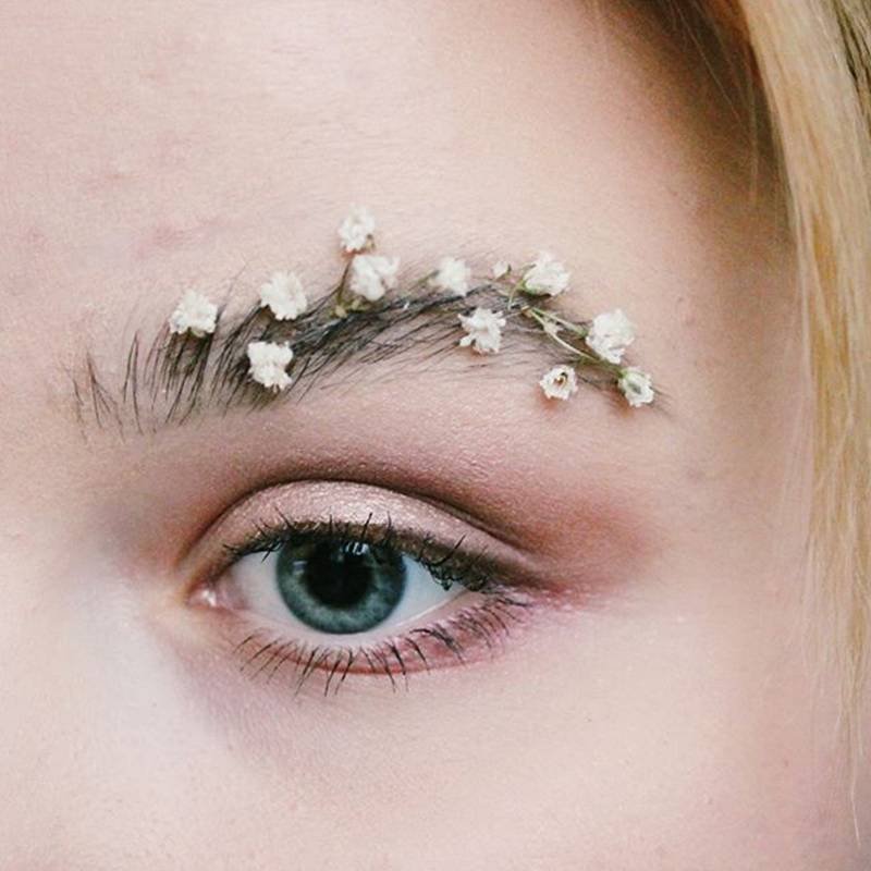 close-up on person's eye with flowers attached to eyebrow