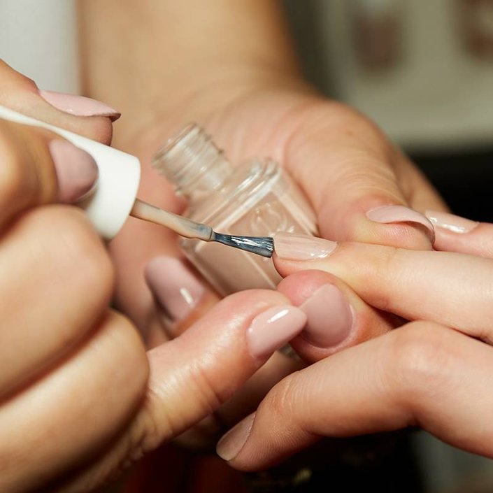 nails being painted with essie nude nail polish