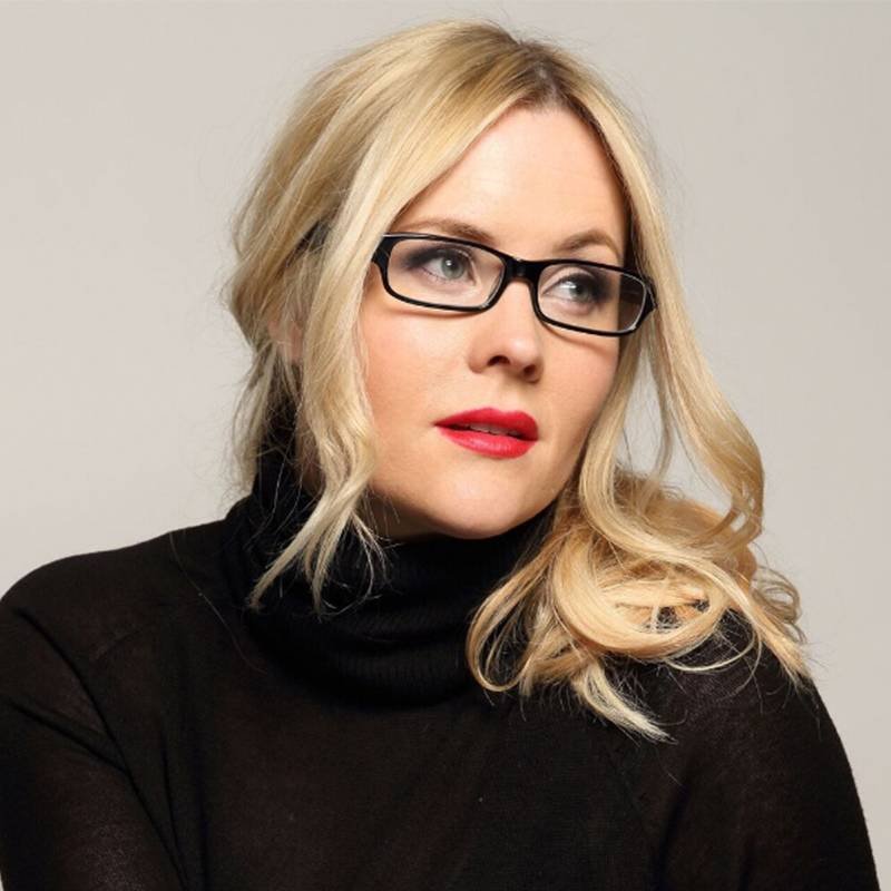 person with blonde hair wearing black glasses and red lipstick