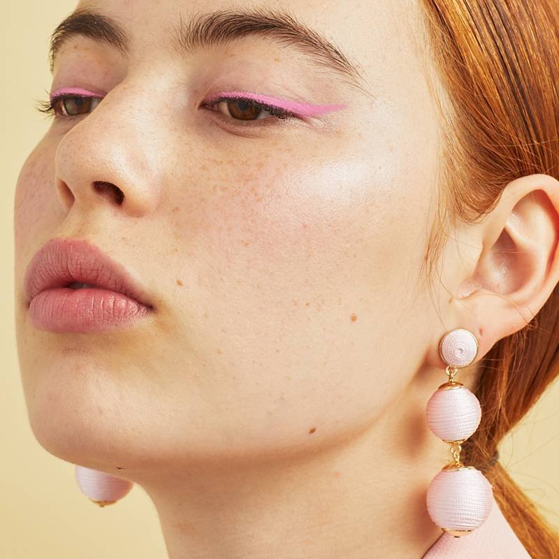 person wearing pink eyeliner and drop earrings