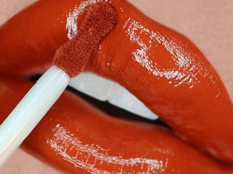 close-up of red liquid lipstick being applied to lips