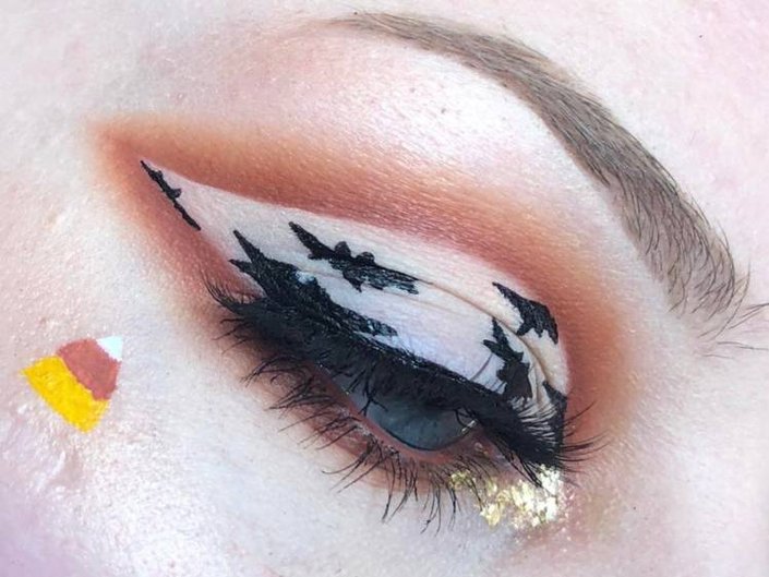close-up of person's eye wearing white eyeshadow with black bats
