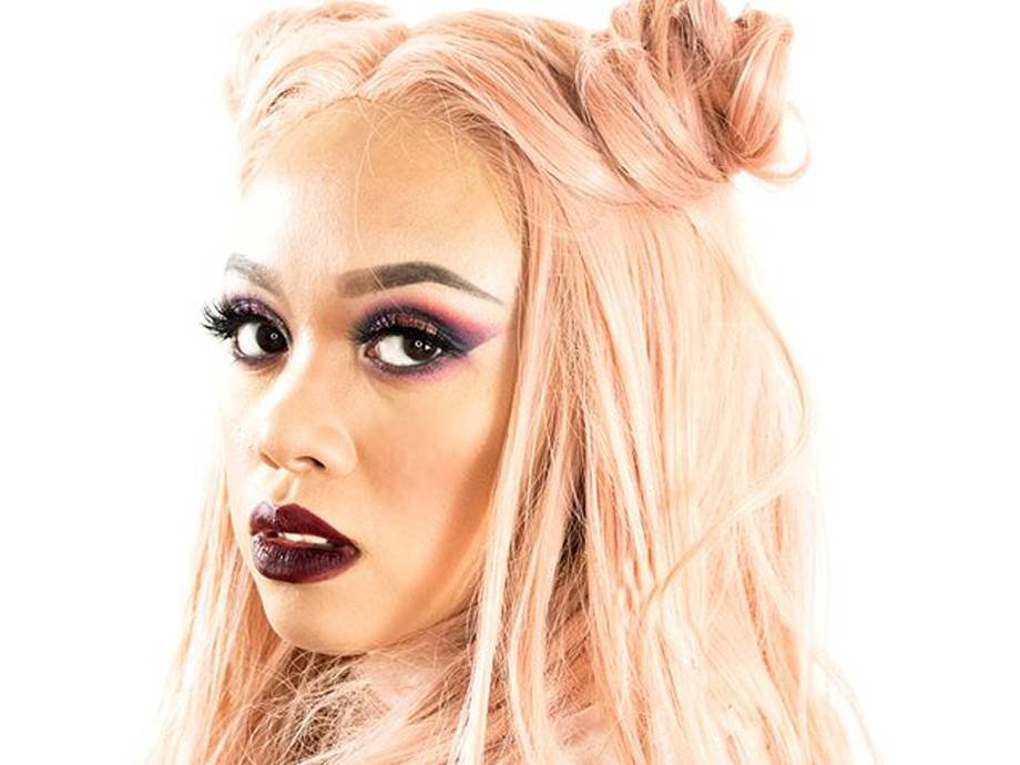 person with pastel pink hair wearing dark smokey eyeshadow and lipstick