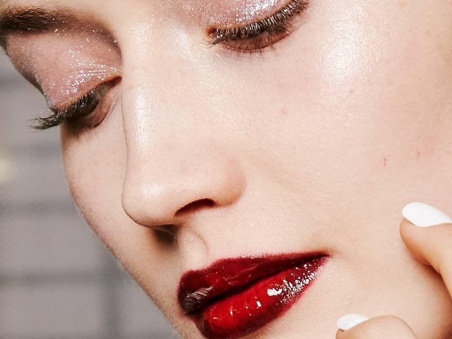 person wearing shimmery eyeshadow and glossy red lipstick