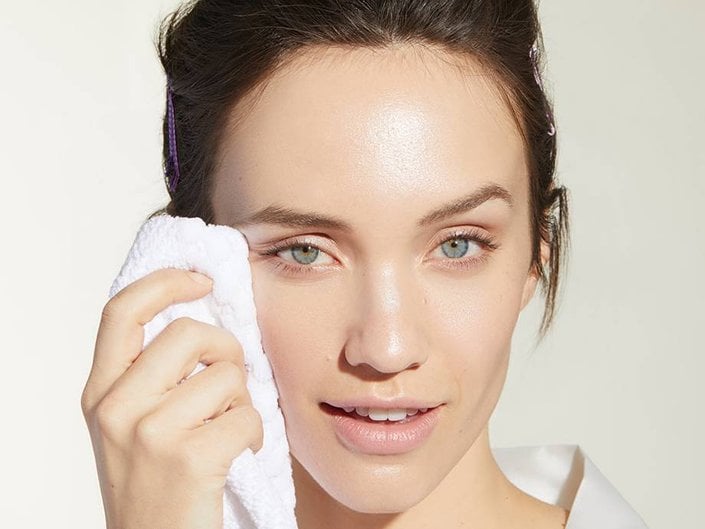 person holding white towel to side of face
