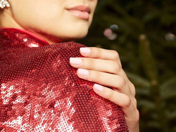 person posing with hand on shoulder with nails painted light pink