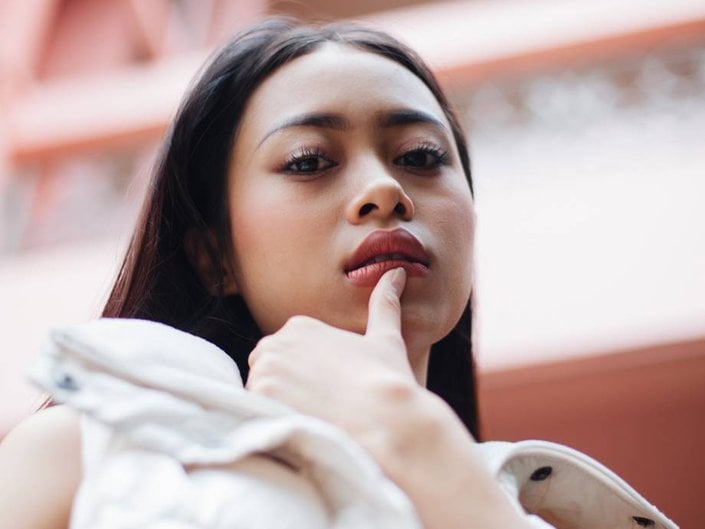 person looking at camera and posing with thumb on bottom lip