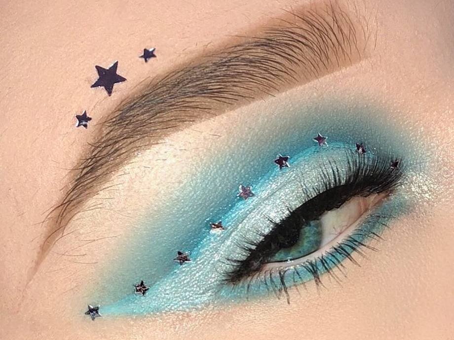 person wearing pastel blue eye makeup with silver star stickers