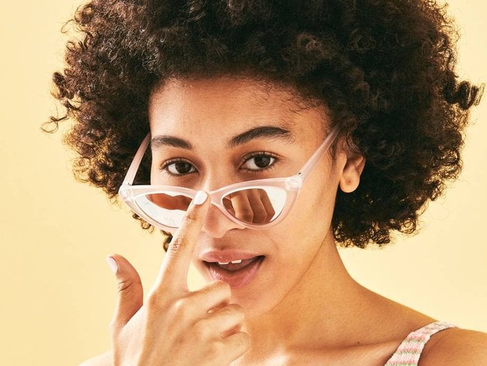 person with naturally curly hair in afro wearing sunglasses on nose