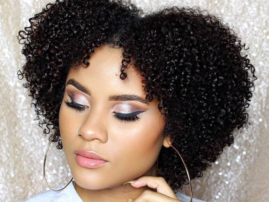 person with naturally curly hair wearing rose gold eyeshadow and black winged eyeliner
