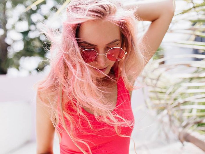 person with pastel pink hair wearing pink sunglasses and a pink tank top