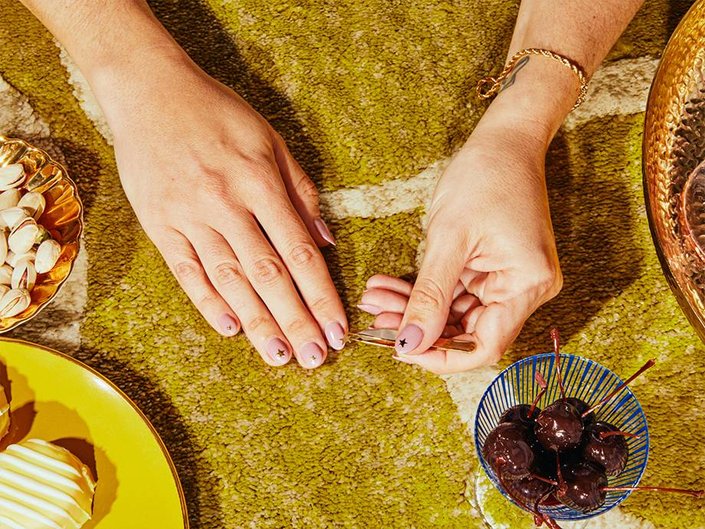 hand applying nail sticker on nail with tweezers