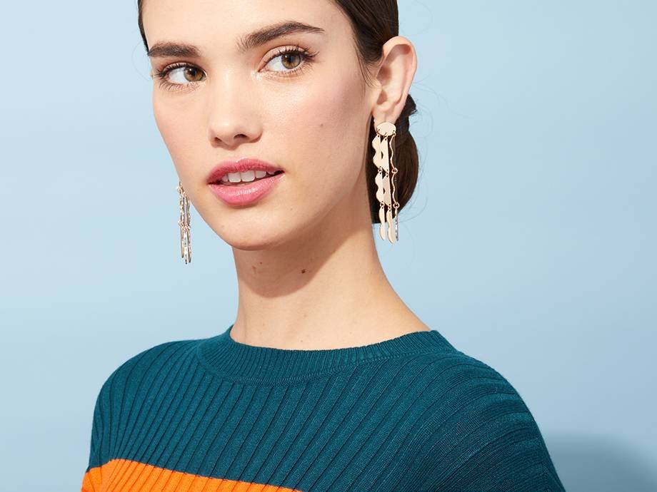 person wearing pink lipstick and chandelier earrings with hair in a low bun