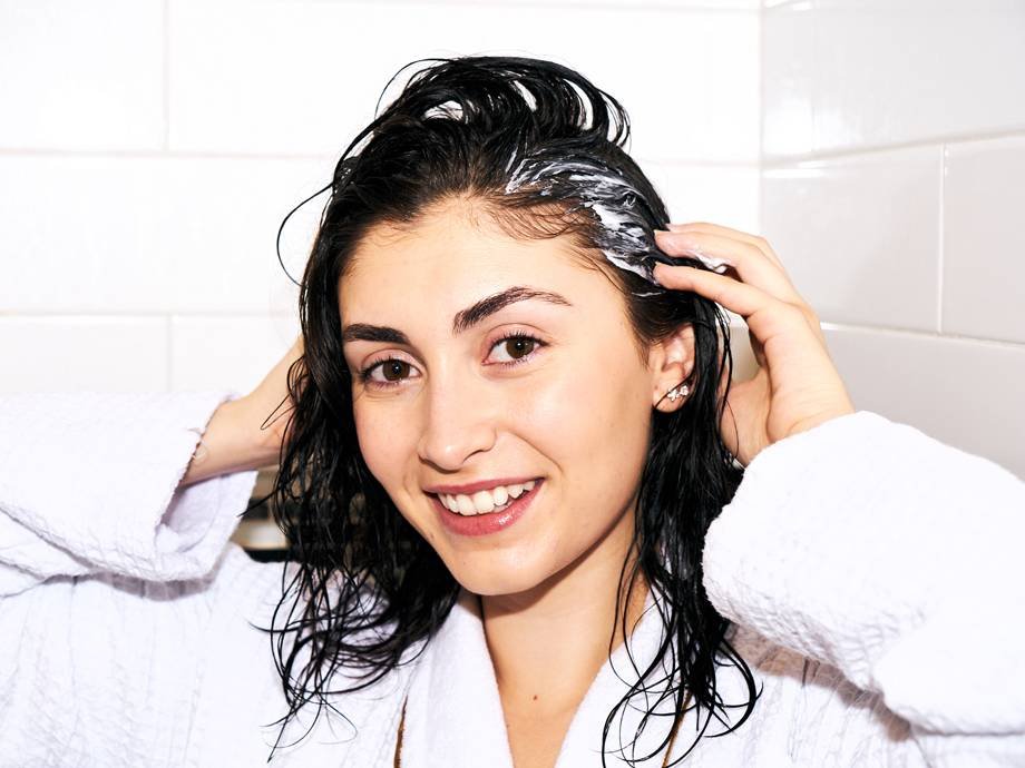 person massaging hair mask into wet hair