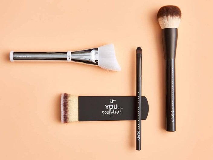 Flat lay photo of makeup brushes on a peach-colored background